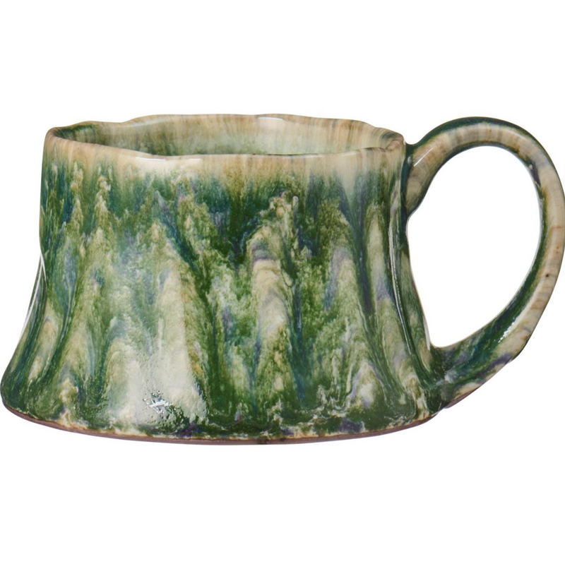 A handmade ceramic mug with a sculptural, organic shape and a handle, featuring a marbled glaze of green, beige, and white.