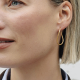 Close-up of a person wearing a gold hoop earring.