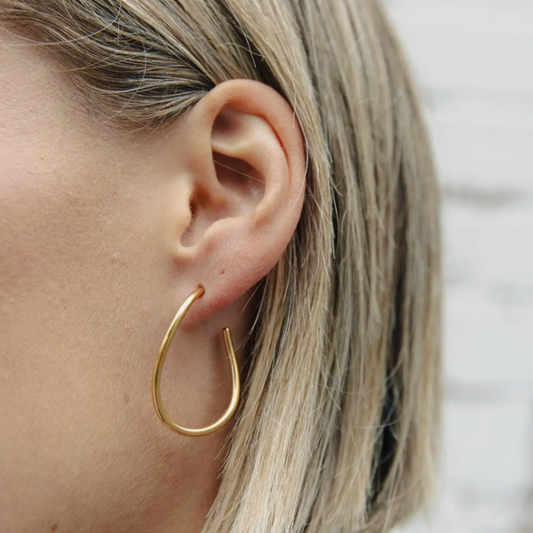 Gold hoop earring worn by a person with blonde hair.