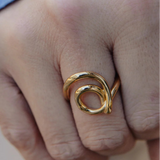 Close-up of a hand wearing a gold ring with a blurred background