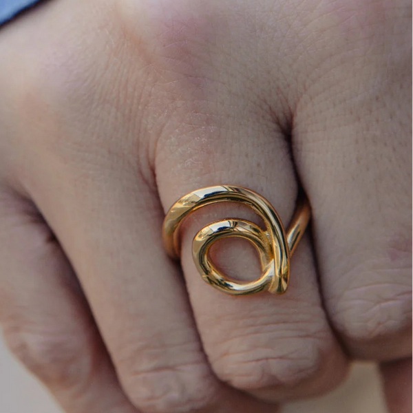 Close-up of a hand wearing a gold ring with a blurred background