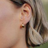 Close-up of a person wearing a gold earring with a blurred background