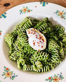 Green pasta with a poached egg on a decorative plate