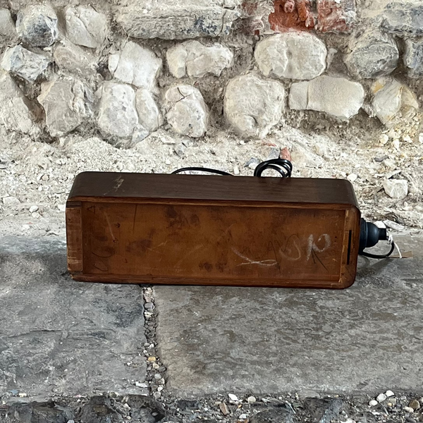 Rust-colored rectangular box on a stone surface with a stone wall background