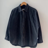 Dark denim shirt on a hanger against a white wall