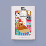 A boxed card set from Stop Clock featuring a festive Christmas illustration with cats, reindeer, and holiday text, shown against a muted blue-gray background.