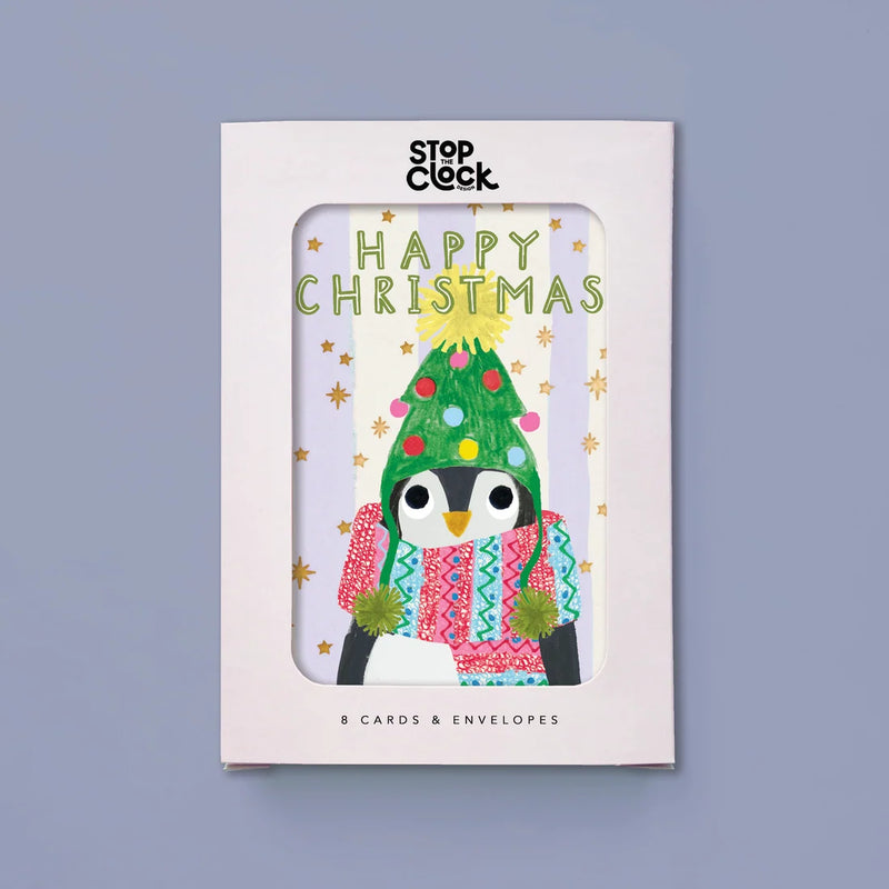 Stop Clock Happy Christmas card and envelope set in a white window box package, featuring a penguin wearing a green Christmas tree hat and colorful scarf against a light gray background.