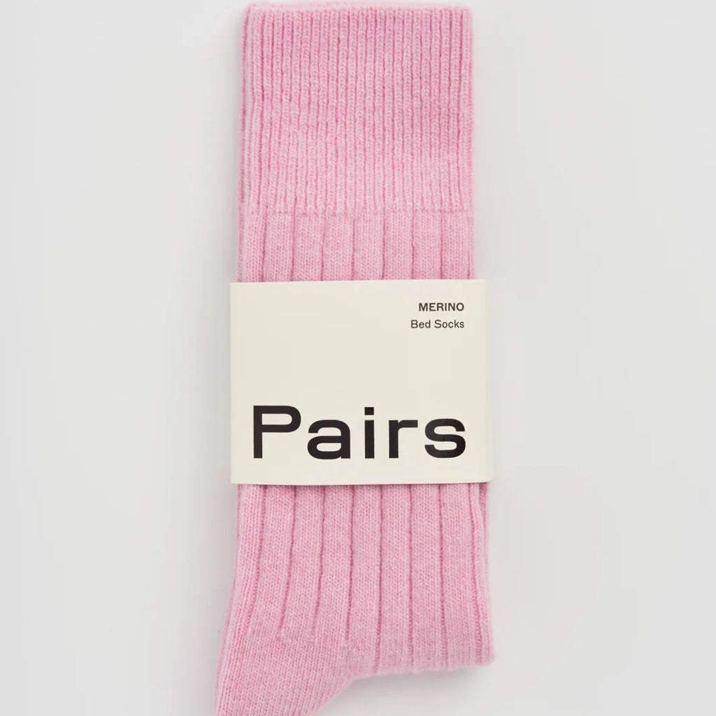 A pair of light pink ribbed knit socks bundled together with a white paper band that reads 'Pairs'.