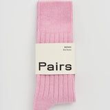 A pair of light pink ribbed knit socks bundled together with a white paper band that reads 'Pairs'.