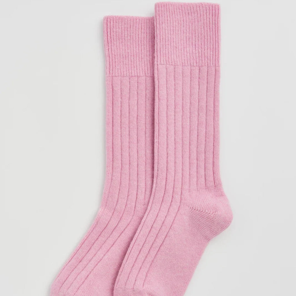 A pair of light pink ribbed crew socks laid flat on a light gray background.