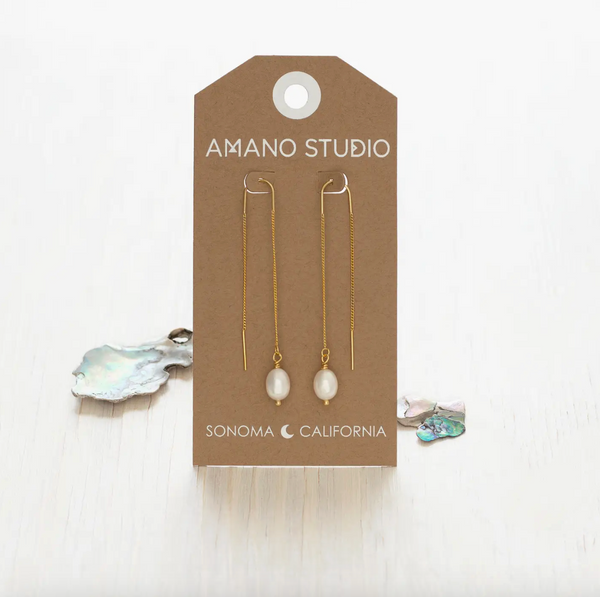 Pair of pearl earrings on a 'Amano Studio' branded card with a white background