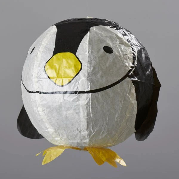 A penguin-shaped hanging paper lantern with a white body, black wings and face details, and a bright yellow beak and feet, shown against a plain gray background.