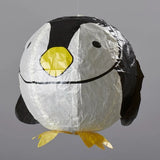 A penguin-shaped hanging paper lantern with a white body, black wings and face details, and a bright yellow beak and feet, shown against a plain gray background.