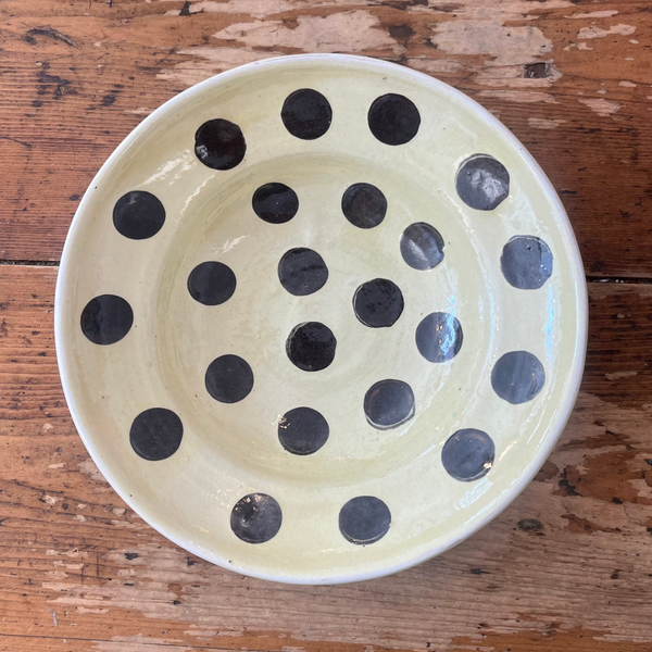 Ceramic bowl with black polka dots on a wooden surface