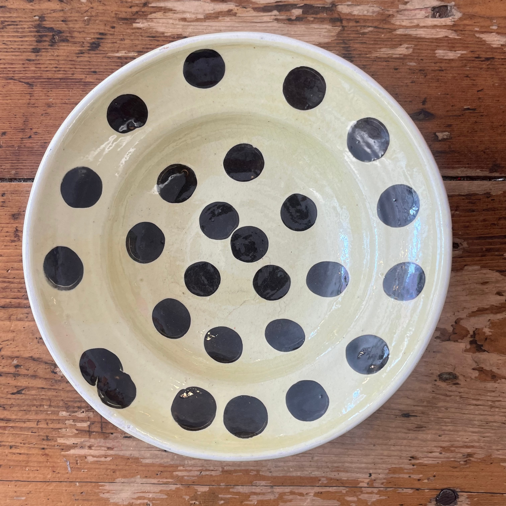 Ceramic bowl with black polka dots on a wooden surface