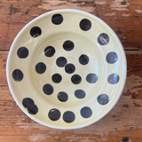 Ceramic bowl with black polka dots on a wooden surface