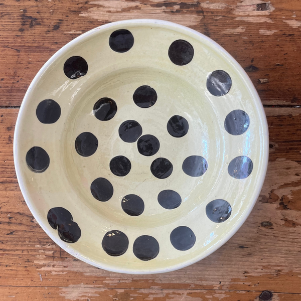 Ceramic bowl with black polka dots on a wooden surface