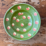 Green ceramic plate with pink and white polka dots on a wooden surface