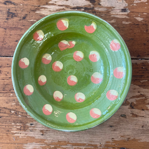 Green ceramic plate with pink and white polka dots on a wooden surface