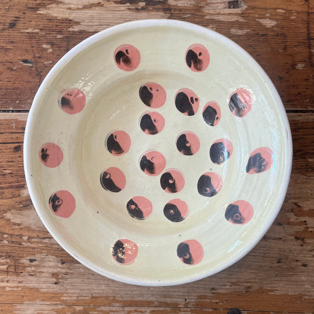 Ceramic bowl with black and pink circular patterns on a wooden surface