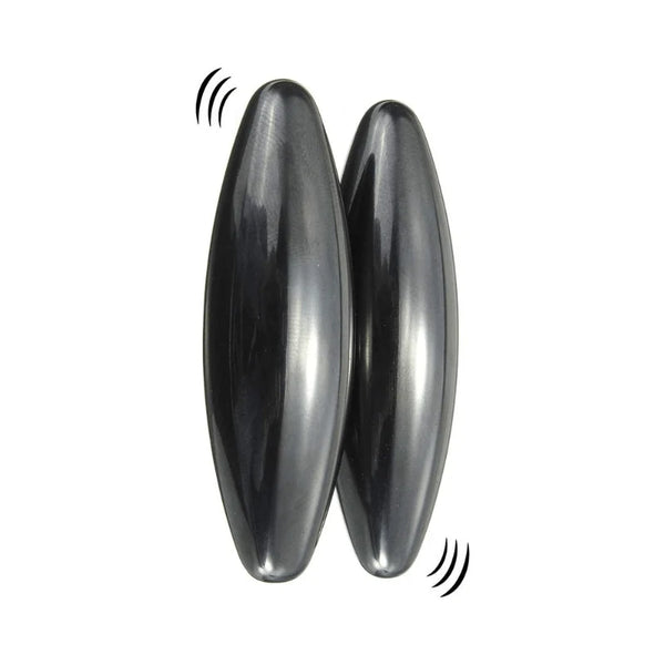 Two dark gray, glossy, teardrop-shaped massage or vibration stones shown on a plain white background with simple black sound wave graphics near them.