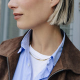 Close-up of a person wearing a brown jacket over a blue shirt with a blurred background