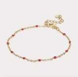 Gold bracelet with red beads on a light beige background