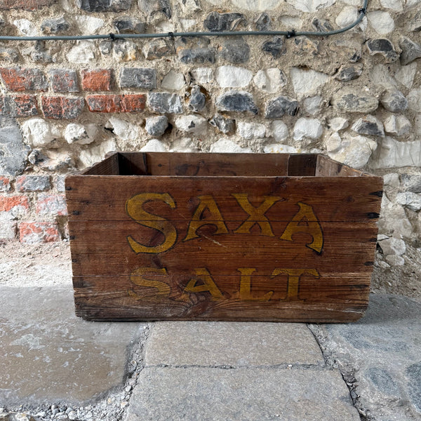 Wooden crate with 'SAXA SALT' text against a stone wall.