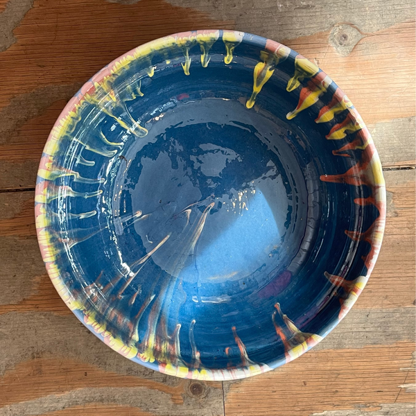 Blue ceramic bowl with multicolored rim on a wooden surface