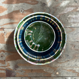 Stack of ceramic bowls with green interior on a wooden surface