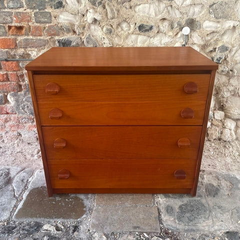 files/Stag_mid-century_modern_three-drawer_wooden_chest_of_drawers_with_a_warm_reddish-brown_finish_and_circular_drawer_pulls_set_against_a_rustic_stone_wall..jpg
