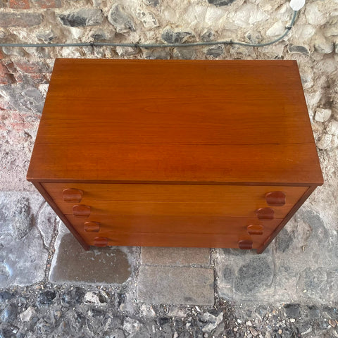 files/Stag_mid-century_modern_wooden_chest_of_drawers_with_a_warm_reddish-brown_finish_and_oval_drawer_pulls_photographed_outdoors_on_a_stone_floor_against_a_rustic_stone_wall..jpg