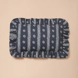 A rectangular dark blue fabric cushion cover with white vertical stripes and snowflake patterns, featuring a ruffled border, displayed on a solid beige background.