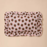 A rectangular ruffled fabric mat featuring a repeating brown sunburst pattern on a light pink background, displayed flat against a solid beige backdrop.