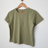 Green t-shirt on a wooden hanger against a white background