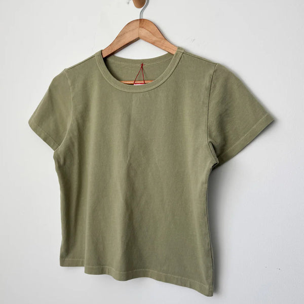Green t-shirt on a wooden hanger against a white background