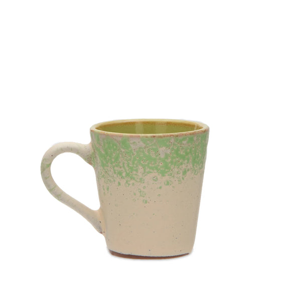 A handmade ceramic mug with a textured, speckled finish in cream and light green, shown against a plain white background.