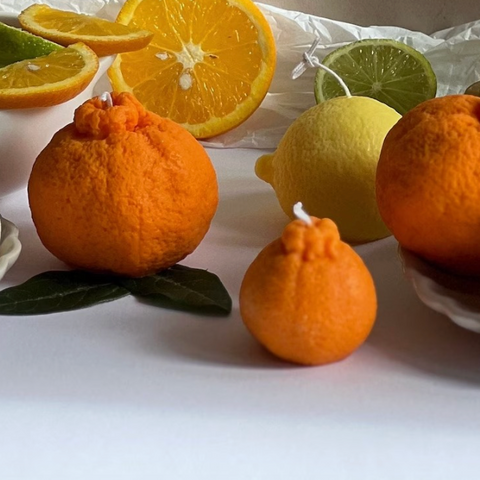 Decorative candles shaped like fruits on a white surface