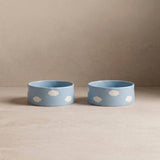 Two blue bowls with white polka dots on a beige surface and background