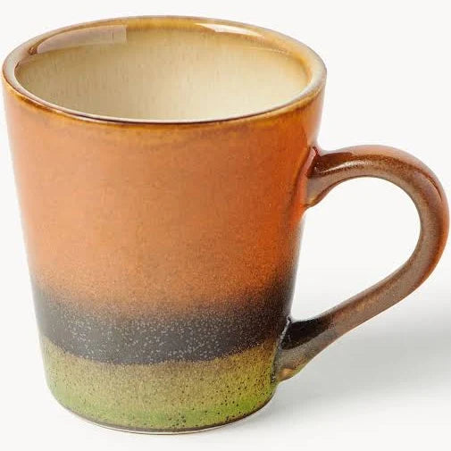 A ceramic coffee mug with a rustic gradient glaze, featuring a warm brown and orange body, a dark charcoal band, and a speckled light green base, shown on a white background.