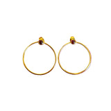 Gold hoop earrings with red gemstones on a white background