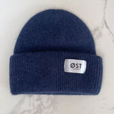 Blue knit beanie with a visible brand label on a marble surface