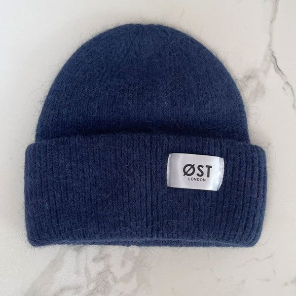 Blue knit beanie with a visible brand label on a marble surface