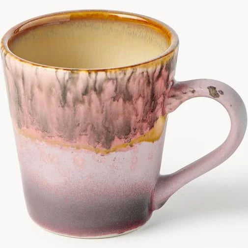A ceramic coffee mug with a marbled glaze transitioning from a warm amber-brown rim to a dusty pink and mauve body, with a speckled purple base and a small chipped detail on the handle.