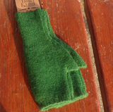 A green, plain wool mix fingerless glove laid flat on a wooden surface with visible brand tag.